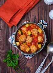 Albondigas, soup or stew, meatballs with vegetables in tomato sauce in a ceramic bowl on a brown wooden background. Mexican cuisine.