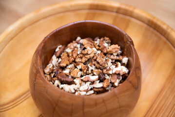 Peeled walnuts in authentic wooden plate on table, healthy snack