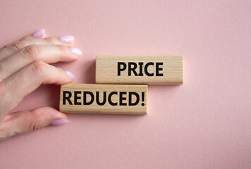 Price reduced symbol. Concept word Price reduced on wooden blocks. Businessman hand. Beautiful pink background. Business and Price reduced concept. Copy space