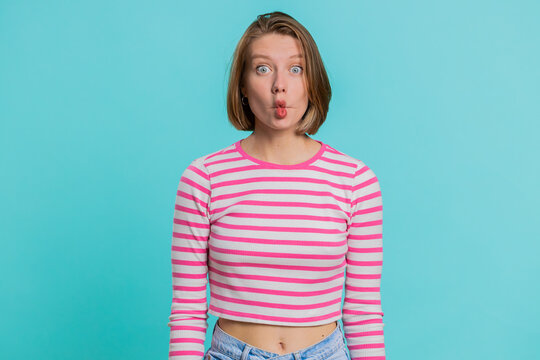 Surprised funny comical playful young woman making fish grimace pout lips, smooching choking and looking with shocked dumb idiotic expression. Lovely female girl doing crazy duck face, fooling around