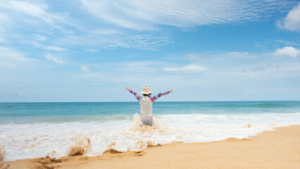 Beautiful day at the beach and blue sky. The back of a young girl is happy touring at Karon Beach, Phuket,Thailand.