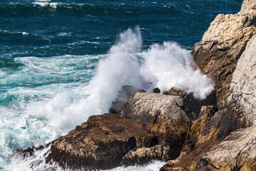 Ocean wave breaking against tall cliff, Point Lobos Nature Preserve, Monterey. Spray thrown high in...