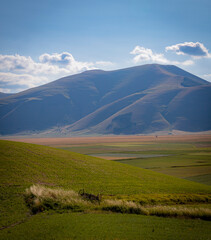 Famous mountain village of Castelluccio di Norcia with beautiful summer landscape at Piano Grande (Great Plain) mountain plateau in the Apennine Mountains on a cloudy day, Umbria, Italy. Low key.