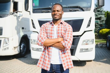 Front view. Young african truck driver is with his vehicle at daytime.