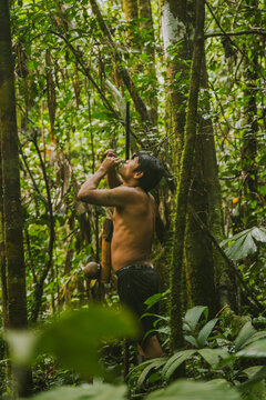 Hunting tribal man shooting poisonous darts in woods