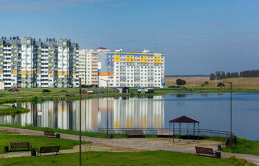 Reflection in the water of a pond in a city of multi-storey colorful residential buildings,...