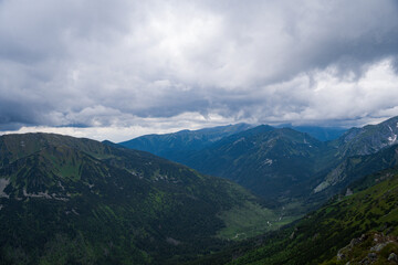 View of mountain peaks in Poland, puffy clouds over the peaks, green mountain slopes