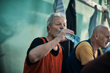 Senior Caucasian man hydrating in the locker room after playing football or soccer