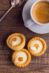 Sweet tarlets. Tasty mini tarts. Mini pie with cream and coffee cup  on kitchen table. Top view.