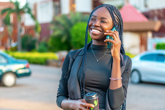 young woman talking on a cell phone while holding a drink