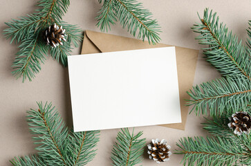 Fototapeta na wymiar Blank Christmas holiday greeting card mockup with envelope and fir tree branches with cones, copy space