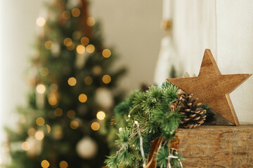 Stylish christmas wooden star, spruce branches on fireplace mantel close up on background of...