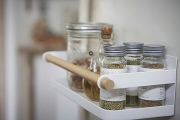 Different spices in jars on the rack in kitchen interior, close up