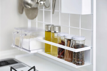 Close up of glass jars with spices on the shelf in kitchen interior