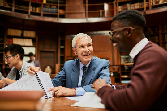 Young African American Student Getting His Paper Graded By A Professor In A College Library