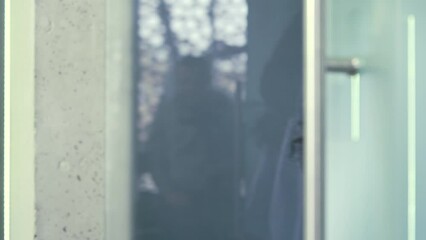 Close up of a female hand opening a glass office door holding a metal doorknob in a modern building. Businesswoman or employee in a shirt opens the door and enters the office to the workplace