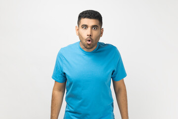 Portrait of amazed shocked surprised unshaven man wearing blue T- shirt standing looking at camera...