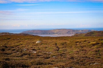 Scenic view of a village in hills against the sea on a sunny day