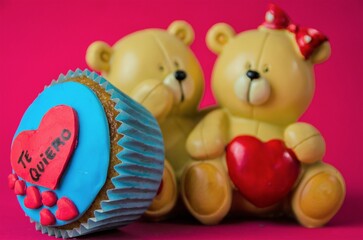 A Valentine's Day cupcake with a heart that says: "I love you" and two bears in the background