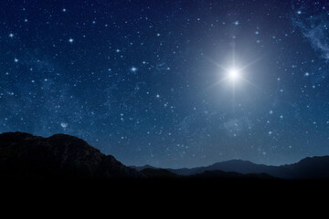 A christmas star shines at night over the mountains of Bethlehem