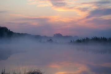 Fototapeta premium Beautiful sunset over a tranquil lake shrouded in fog in an idyllic atmosphere