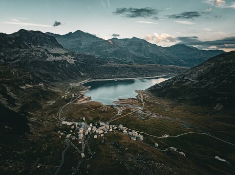 Aerial view of a tranquil lake surrounded by mountains on a cloudy day in Montespluga, Italy