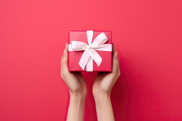 A woman's hands holding a red gift box with a white bow created with Generative AI technology