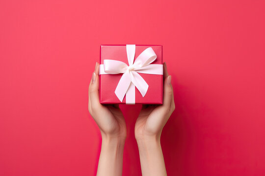 A woman's hands holding a red gift box with a white bow created with Generative AI technology