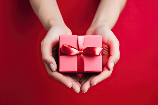 Anonymous woman's hands holding a red gift box with a white bow created with Generative AI technology - Powered by Adobe