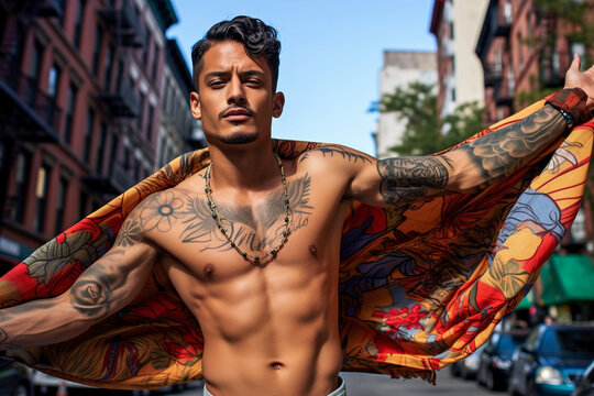 Generative AI illustration from below of Young tattooed chicano with a bare torso holding a flag looking at the camera in town blurred background