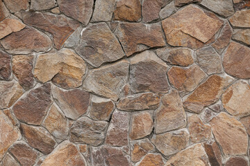 The texture of natural stone masonry on the fence near the house