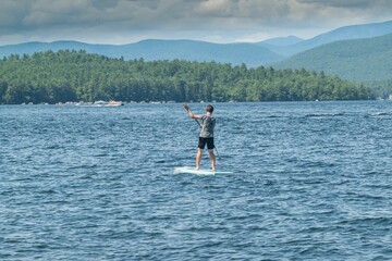 Paddle boarder enjoying a view of the White Mountains cruising on New Hampshire's Lake Winnipesaukee