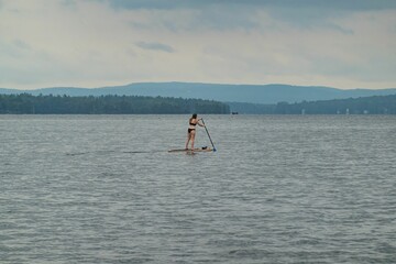 Naklejka premium Paddle boarder enjoying a view of the White Mountains cruising on New Hampshire's Lake Winnipesaukee