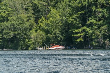 Vibrant red speedboat peacefully docked in the blue waters of Lake Winnipesaukee in New Hampshire