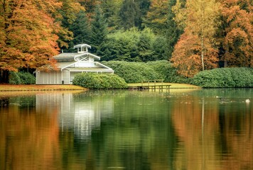 Fototapeta na wymiar Scenic view of a wooden house near a tranquil lake in a forest in autumn