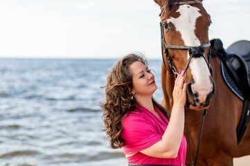 Closeup shot of a young happy female posing with her horse on a beach