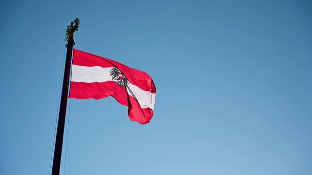 Slow motion of Austrian flag flying on the wind. Waving national flag of Austria on flagpole against blue sky.  