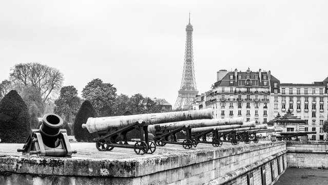 Historical cannons at Les Invalides and parisian cityscape with Eiffel Tower, Paris, France. Black and white photography. Black and white photography.