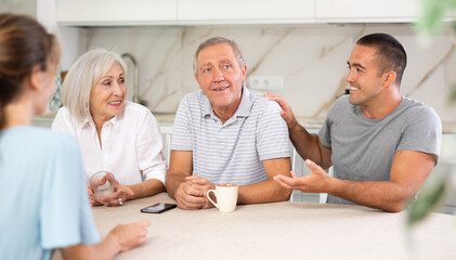 Young married couple and senior parents talk about home life