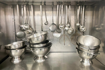 kitchen tools ladles and containers placed in a stainless steel cabinet