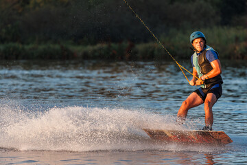 An athlete performs a trick on the water. Park at sunset. Wakeboard rider