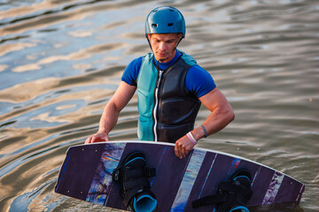 An athlete performs a trick on the water. Park at sunset. Wakeboard rider
