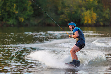 An athlete performs a trick on the water. Park at sunset. Wakeboard rider