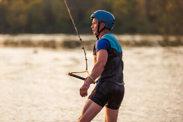 An athlete performs a trick on the water. Park at sunset. Wakeboard rider