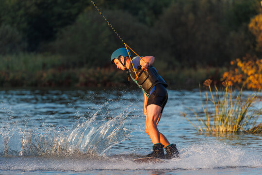 An athlete performs a trick on the water. Park at sunset. Wakeboard rider