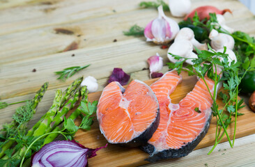 Natural vegetarian food frame of raw salmon steaks, fresh vegetables, mushrooms, herbs and seasonings on wooden surface