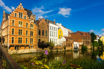 Fototapeta na wymiar Picturesque summer view of Ghent with typical Flemish style townhouses located on banks of river Leie flowing through city center, Belgium..