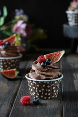 Chocolate cupcake with fig and berries on top.