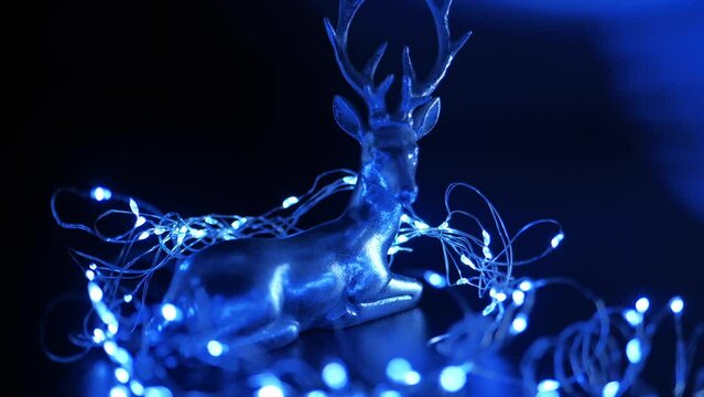 Christmas decorations. Silver deer and shining blue garland on a black background. 4k footage