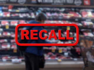 Blurred background of a woman shopping inside a grocery store with the red text Recall in the...